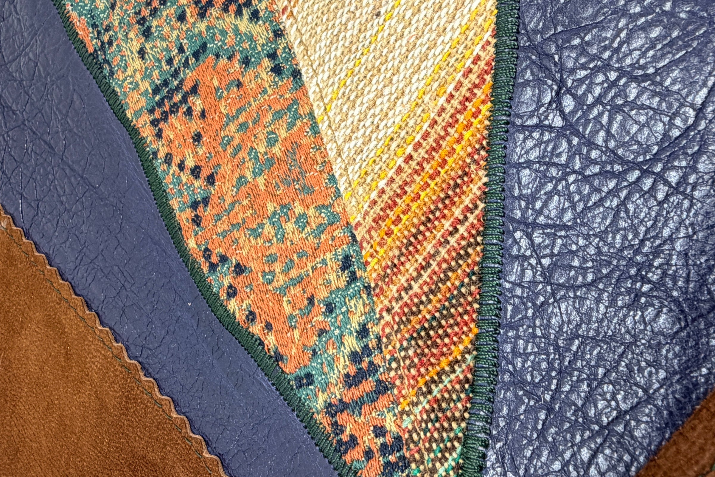 Close-up of leather and vintage fabric patchwork sewn with different textures and colors.