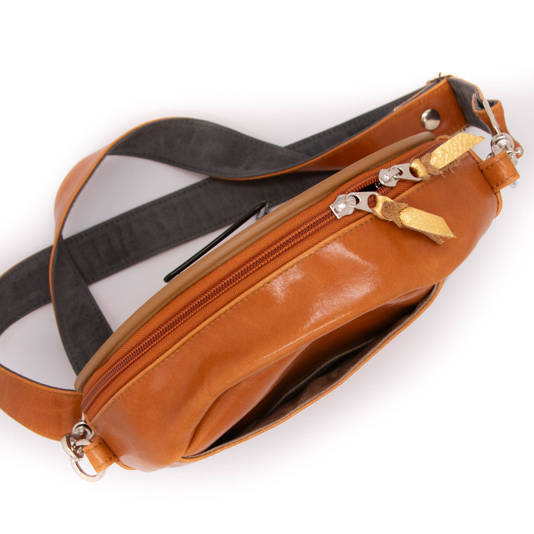 Brown leather bag with gold zipper pull on a white background#color_egypt-air-orange-gold