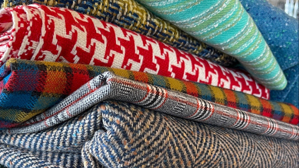 Stack of various plaid vintage fabrics on a tiled floor