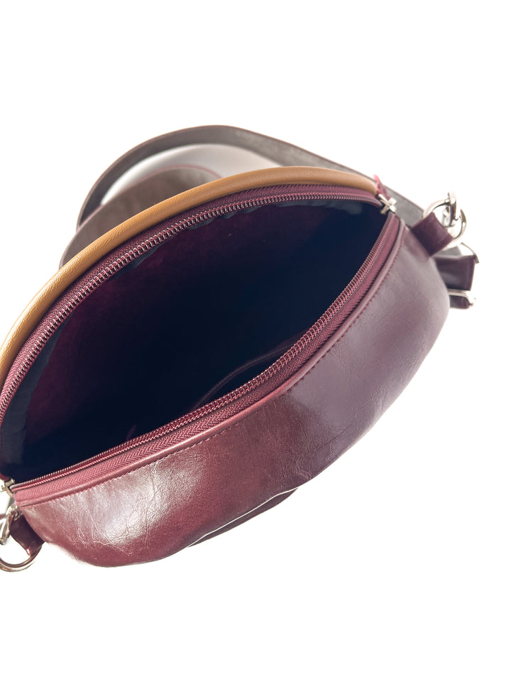 Close-up of a maroon handbag with a visible zipper on a white background#color_golden-floral-chenille