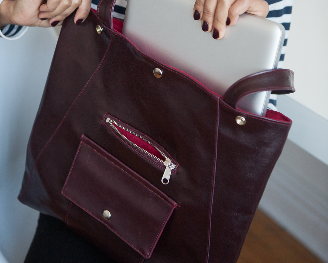 Woman holding a wine machine washable leather bag with a laptop inside