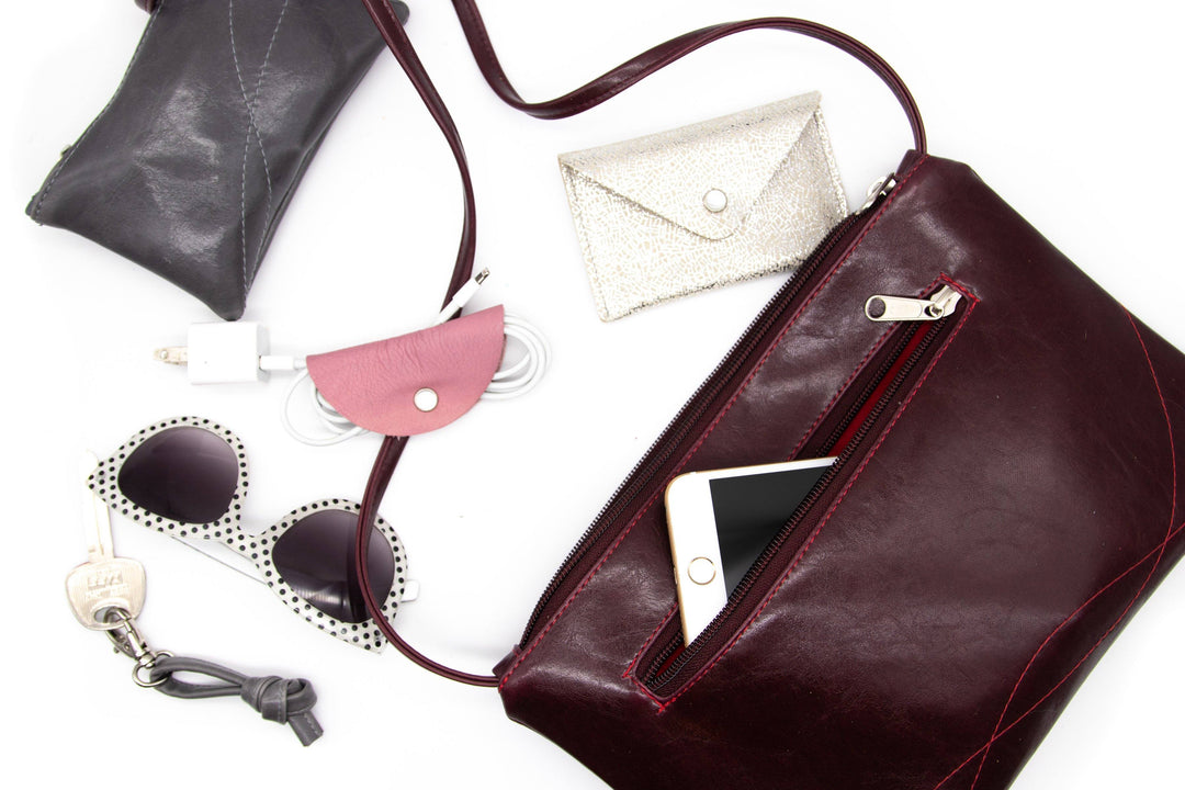 phone sunglasses wallet and keys spilling out of Bossa Nova Medium Crossbody purse - Wine